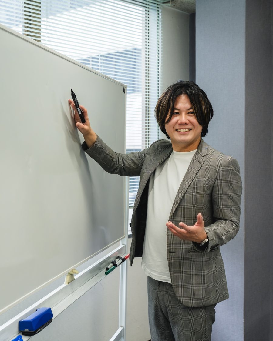 ホワイトボードの前で話すユウキ先生